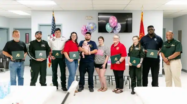 A group of first responders take a group picture with the family of the infant they helped save.