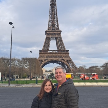 Richard Belle and his wife pose in front of the Eiffel Tower.